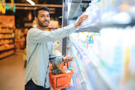 Portrait of handsome young Indian man standing at grocery shop or supermarket, Closeup. selective focusの写真素材