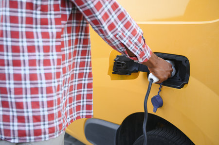 African American Man stands next to electric delivery vans at electric vehicle charging station.の写真素材