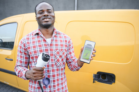 African american man charging car at vehicle charging station.の写真素材