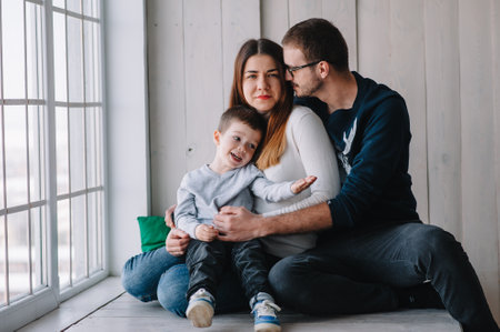 happy family of mother, father and child son playing and cuddling, at home on floor near a big window. family conceptの写真素材