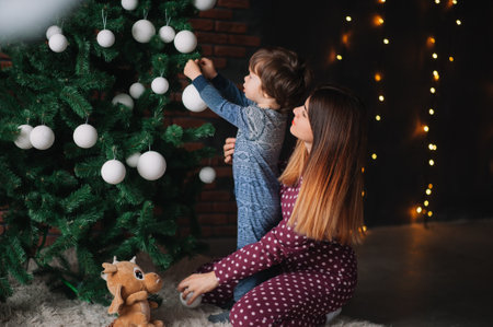 Happy mother with a little boy decorating a Christmas tree at home. Concept of Merry Christmas, New...
