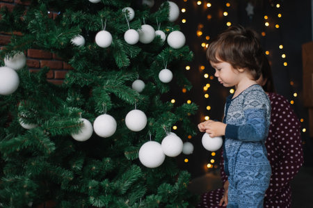A little boy adorns a Christmas tree at home. Concept Happy Christmas, New Year, holiday, winter, childhood.の写真素材