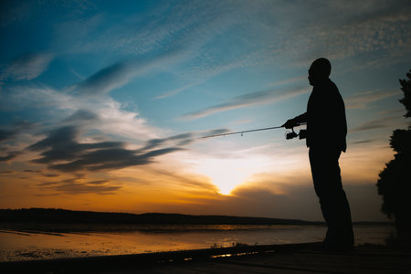 Fishing. spinning at sunset. silhouette of a fishermanの写真素材