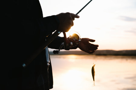 The fisherman's hands, holds the spinning rod, rotates the coil handle. Hobby and activityの写真素材