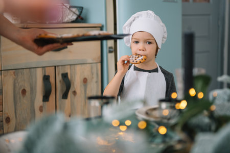 Young happy mom and her baby cook cookies at home in the kitchen. Christmas Homemade Gingerbread. cute boy with mother in white uniform and hat cooked chocolate cookies.の写真素材
