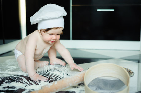 Little boy sitting on carpet in kitchen playing with cooking pots. Cute boy cooking in the kitchen at home.の写真素材