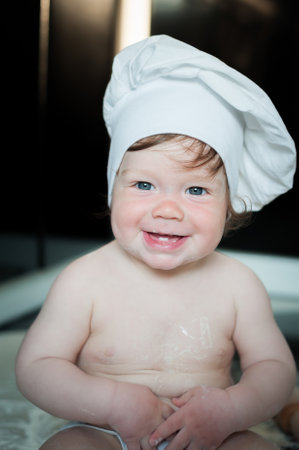 Little boy sitting on carpet in kitchen playing with cooking pots. Cute boy cooking in the kitchen at home.の写真素材