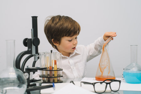 The boy with a microscope and various colorful flasks on a white background. A boy doing experiments in the laboratory. Explosion in the laboratory. science and education.の写真素材
