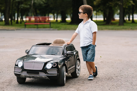 Cute boy riding a black electric car in the park. Funny boy rides on a toy electric car. little happy boy riding a black electric car in the park. copyspace.の写真素材