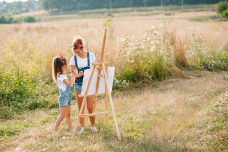Young mother and her daughter have fun, mother's day. smiling mother with beautiful daughter draws natureの写真素材