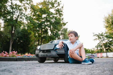 Cute boy riding a black electric car in the park. Funny boy rides on a toy electric car. little happy boy riding a black electric car in the park. copyspace.の写真素材