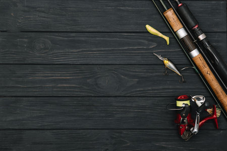 Fishing tackle - fishing spinning, hooks and lures on darken wooden background. top viewの写真素材