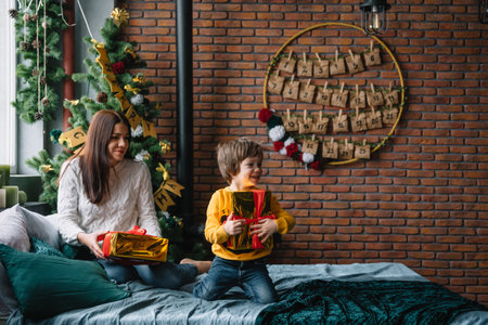 Young beautyful mother with the cute son near Christmas tree with gifts. merry christmasの写真素材