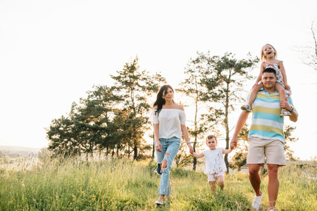 Color photo of smiling young parents and two children, rest and have fun in nature. Love, family and happy childhood lifestyle conceptの写真素材