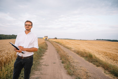 young farmer engineer standing on wheat field.
