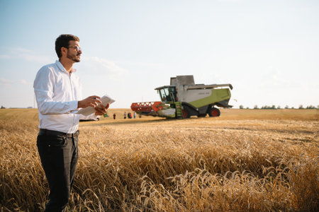 Happy farmer in the field checking corn plants during a sunny summer day, agriculture and food...
