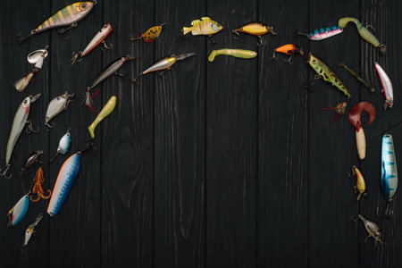 Fishing tackle - fishing spinning, hooks and lures on darken wooden background. top view.の写真素材
