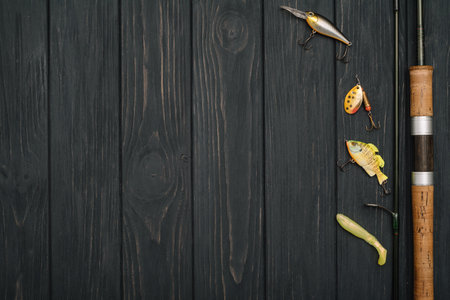 Fishing tackle - fishing spinning, hooks and lures on darken wooden background. top view.の写真素材