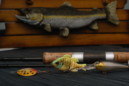 Fishing tackle - fishing spinning, hooks and lures on darken wooden background. top view.