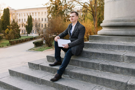 Two confident business colleagues walking on office terrace. Mid adult business man and woman discussing document outdoors on coffee break. Working during break conceptの写真素材