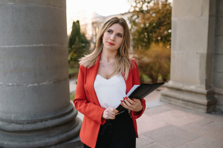 Portrait of business women in feeling of concentrate stress and see stand and hold the paper file sheet in the outdoor pedestrian walk way with the city space of exterior modern facade buildingの写真素材