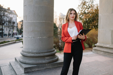 Portrait of business women in feeling of concentrate stress and see stand and hold the paper file sheet in the outdoor pedestrian walk way with the city space of exterior modern facade buildingの写真素材