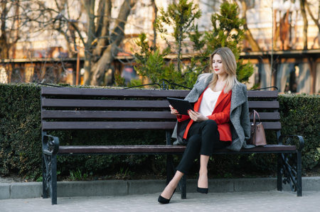 Two confident business colleagues walking on office terrace. Mid adult business man and woman discussing document outdoors on coffee break. Working during break conceptの写真素材
