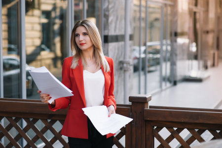 Portrait of business women in feeling of concentrate stress and see stand and hold the paper file sheet in the outdoor pedestrian walk way with the city space of exterior modern facade building.の写真素材