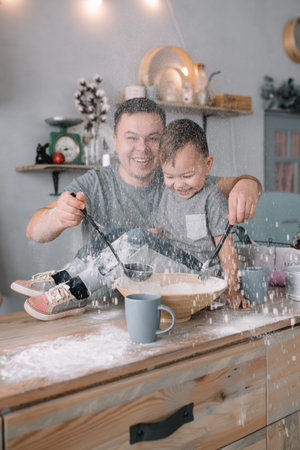 Young man and his son with oven sheet in kitchen. Father with little son on the kitchenの写真素材