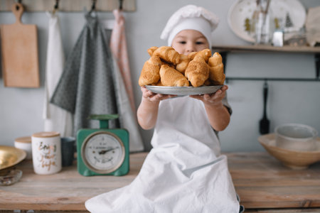 Young boy cute on the kitchen cook chef in white uniform and hat near table. homemade gingerbread....