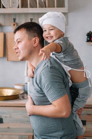 Young man and his son with oven sheet in kitchen. Father with little son on the kitchen.