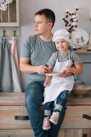 Young man and his son with oven sheet in kitchen. Father with little son on the kitchen.の写真素材