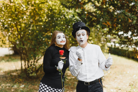 mime artist blowing a bubble through wand on green backgroundの写真素材