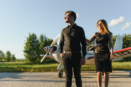 Happy young couple laughing and having fun on runway near private aircraftの写真素材