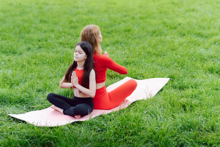 Mother practicing yoga with her daughter in the open air.の写真素材