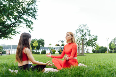 A young mother and daughter in sportswear do yoga together in a Park. The concept of a family holiday. Sports, fitness, meditationの写真素材