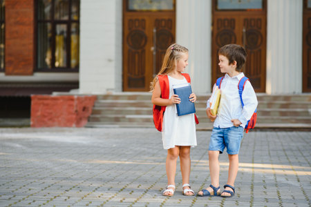 Happy children - boy and girl with books and backpacks on the first school day. Excited to be back...