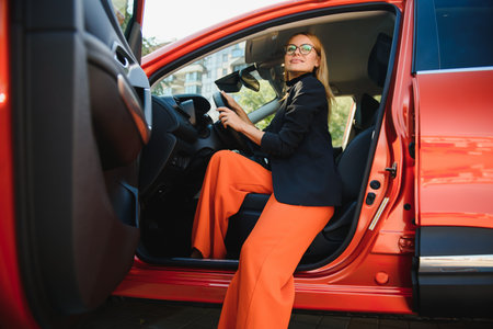 Beautiful mature woman in business suit driving a car to office. Businesswoman drive a car in city.