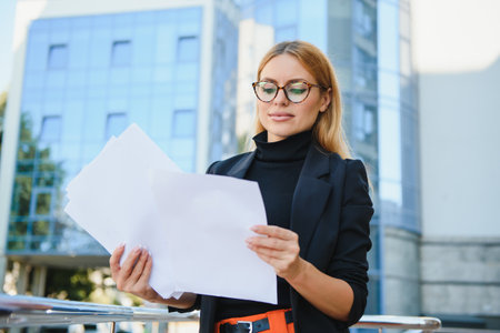 business woman on the street is looking at a document. Scrolls a folder near the building.の写真素材