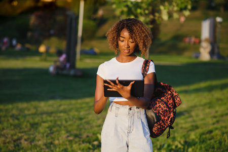Online communication, education or work concept. Pretty African American lady with tablet computer at parkの写真素材