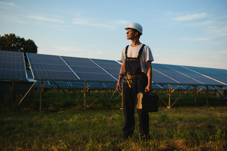 Male engineer in helmet standing near solar panels. Concept ecology protection.
