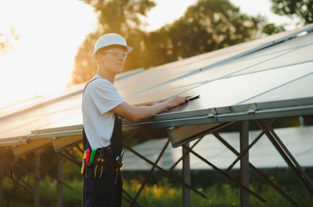 The portrait of a young engineer checks with tablet operation with sun, cleanliness on field of photovoltaic solar panels. Concept: renewable energy, technology, electricity, service, green power.の写真素材