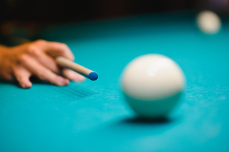 game of billiards the hand of a man with a billiard cue aims at a billiard ball
