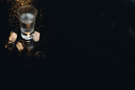 Vodka shots with ice on black table, copy space