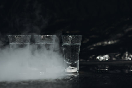 Vodka shots with ice on black table, copy spaceの写真素材
