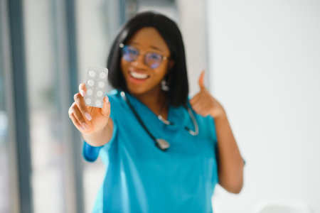 smiling african american nurse with stethoscope holding pillの写真素材