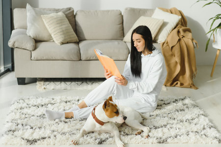 A beautiful young woman reading her favorite book with her dogの写真素材