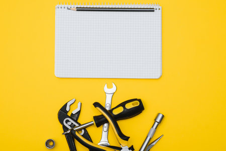 Tools top view on yellow background. Plier, open wrenches, screwdrivers and staple gun flat lay with...