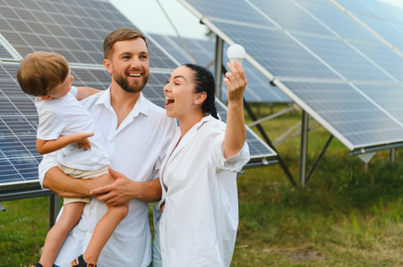 The concept of renewable energy. Young happy family near solar panels.