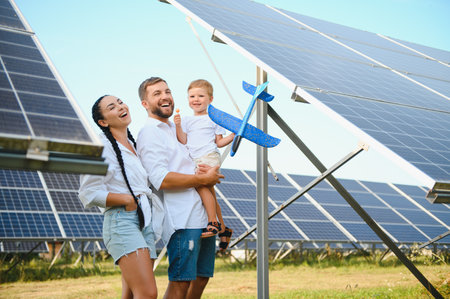 The concept of green energy. Happy family walking and having fun in solar panel field. Green energyの写真素材